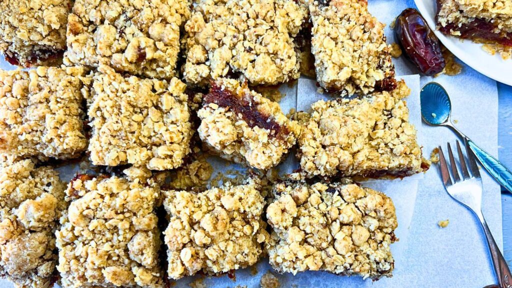 An overhead view of date squares on a piece of parchment paper. One square is turned on it's side.