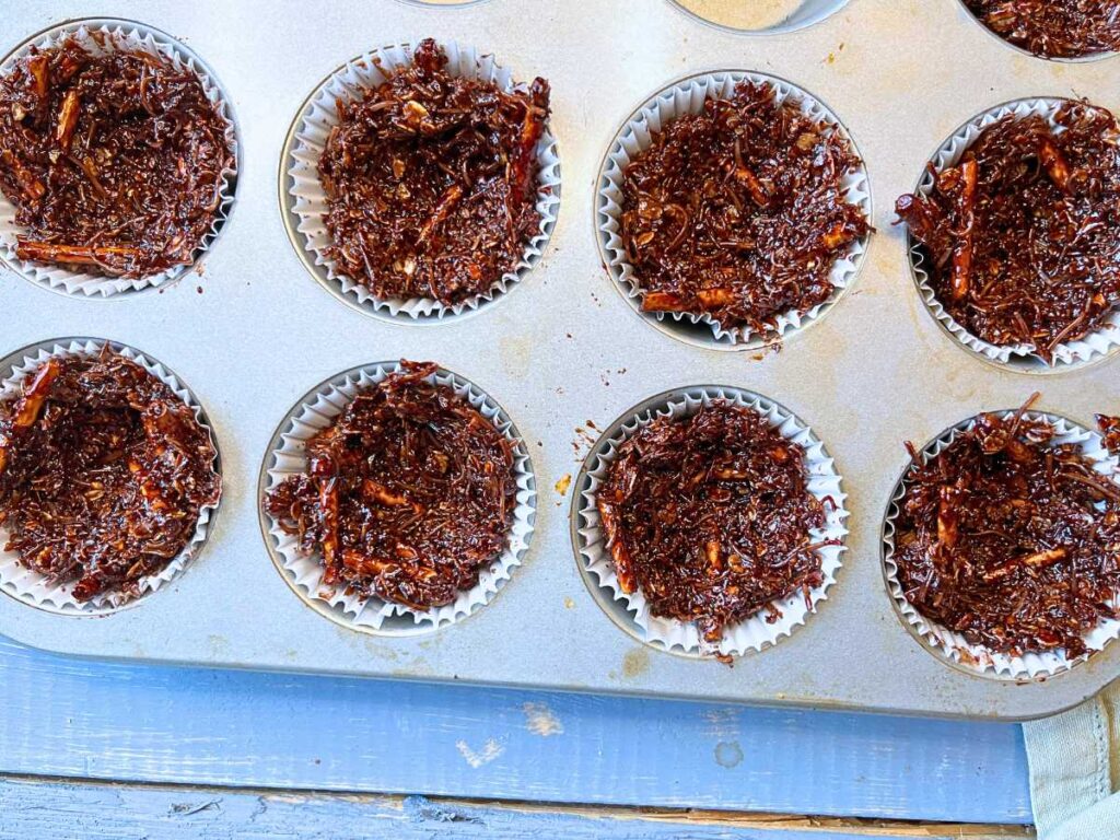 Chocolate nests in a lined muffin tin.