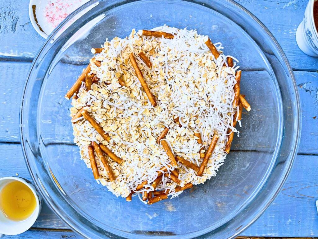 Oats, coconut, and pretzels in a class bowl.