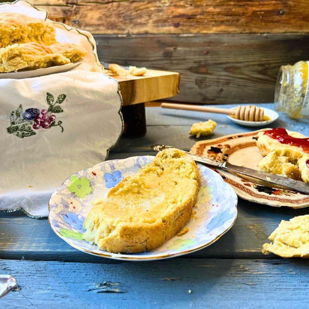 A slice of bannock on a blue floral plate. There is more of the loaf in the background.