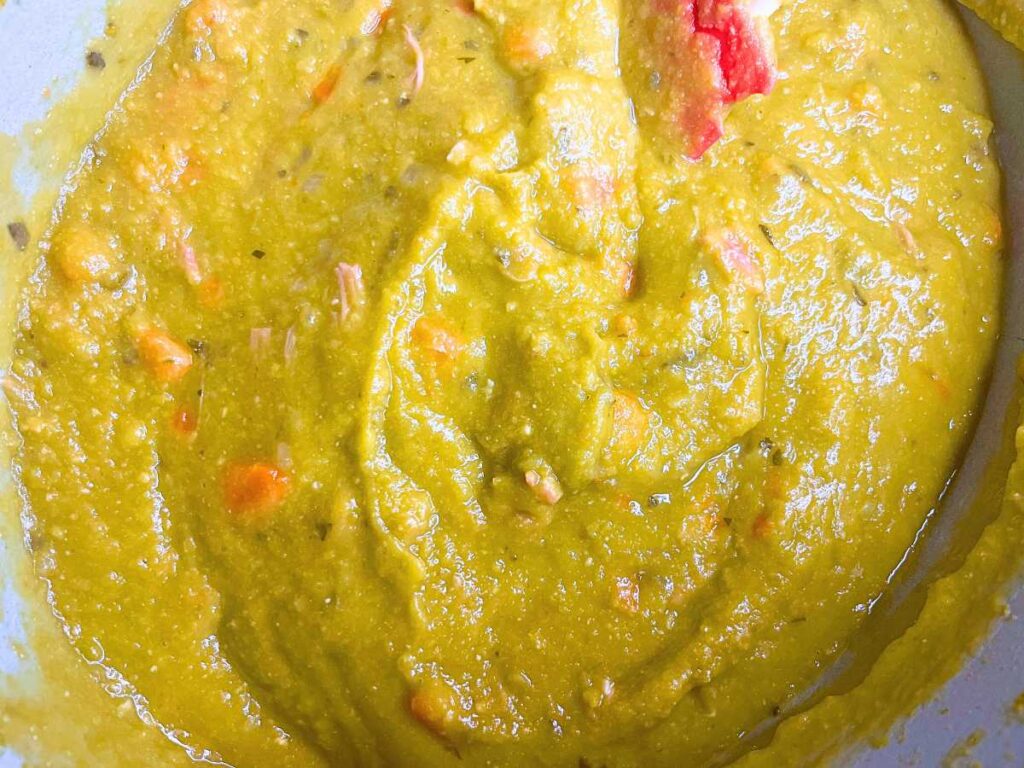 An overhead close up look at a pot of cooked split-pea soup.