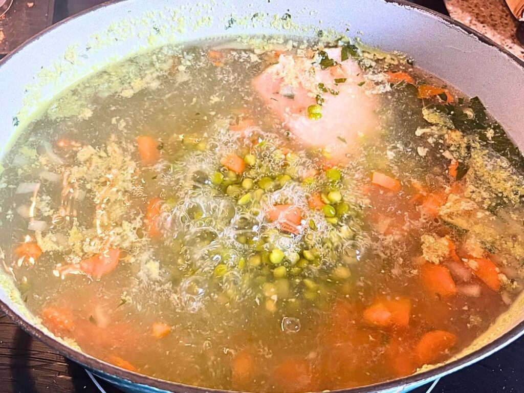 A pot of boiling vegetables, water, and salt pork.