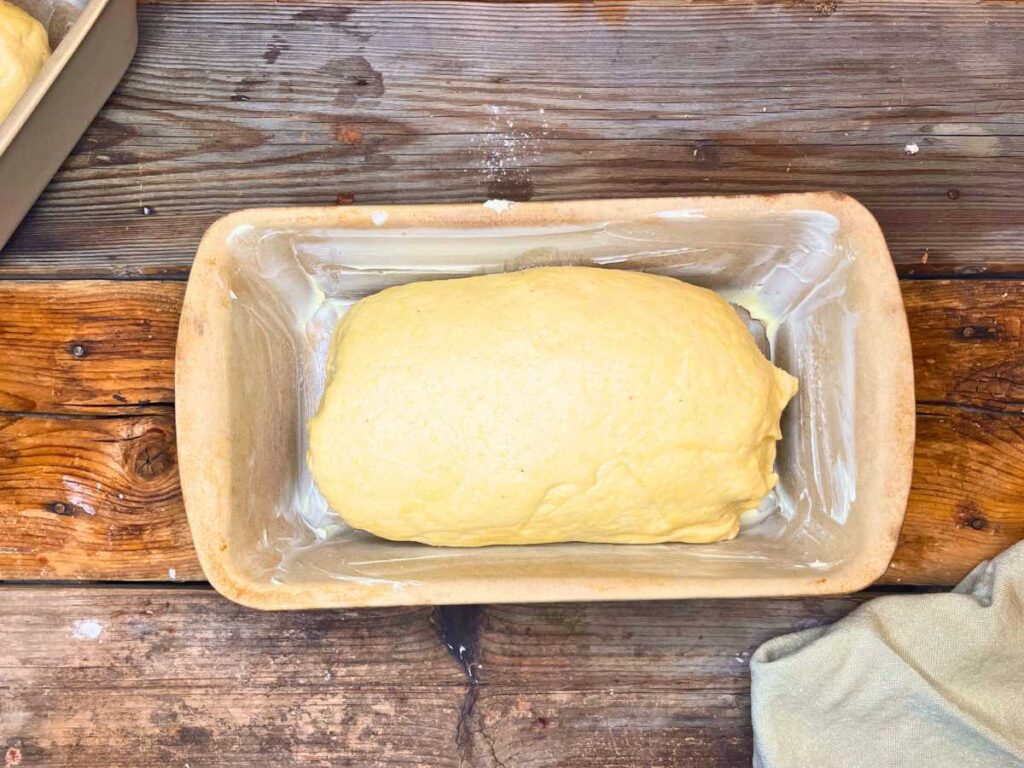 A stone loaf pan with cornmeal bread dough inside.