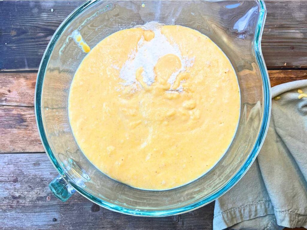 A large glass bowl with flour and a cornmeal mixture inside.