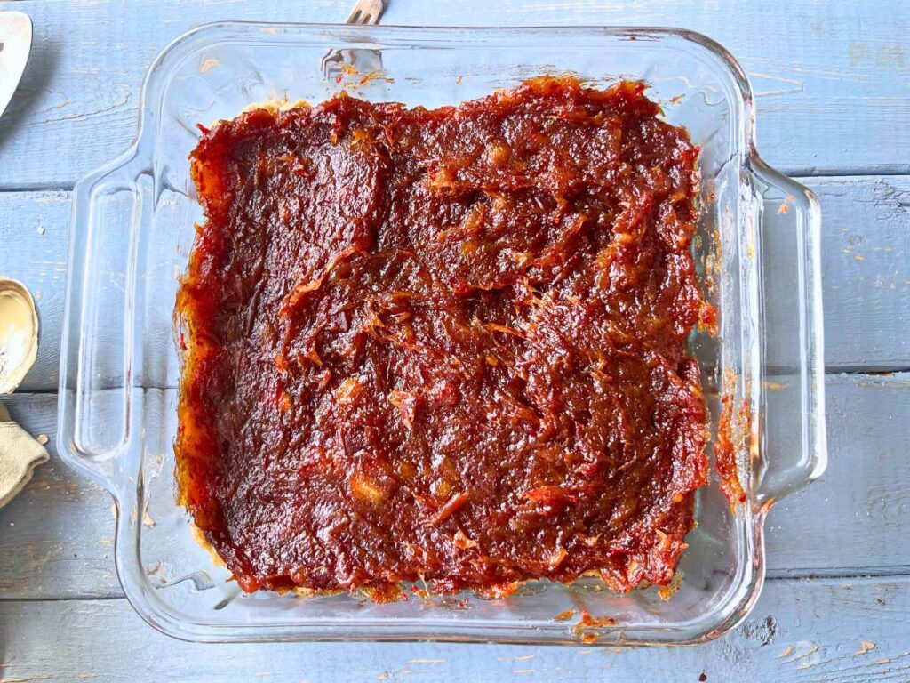 A glass square casserole dish with a date filling spread inside.