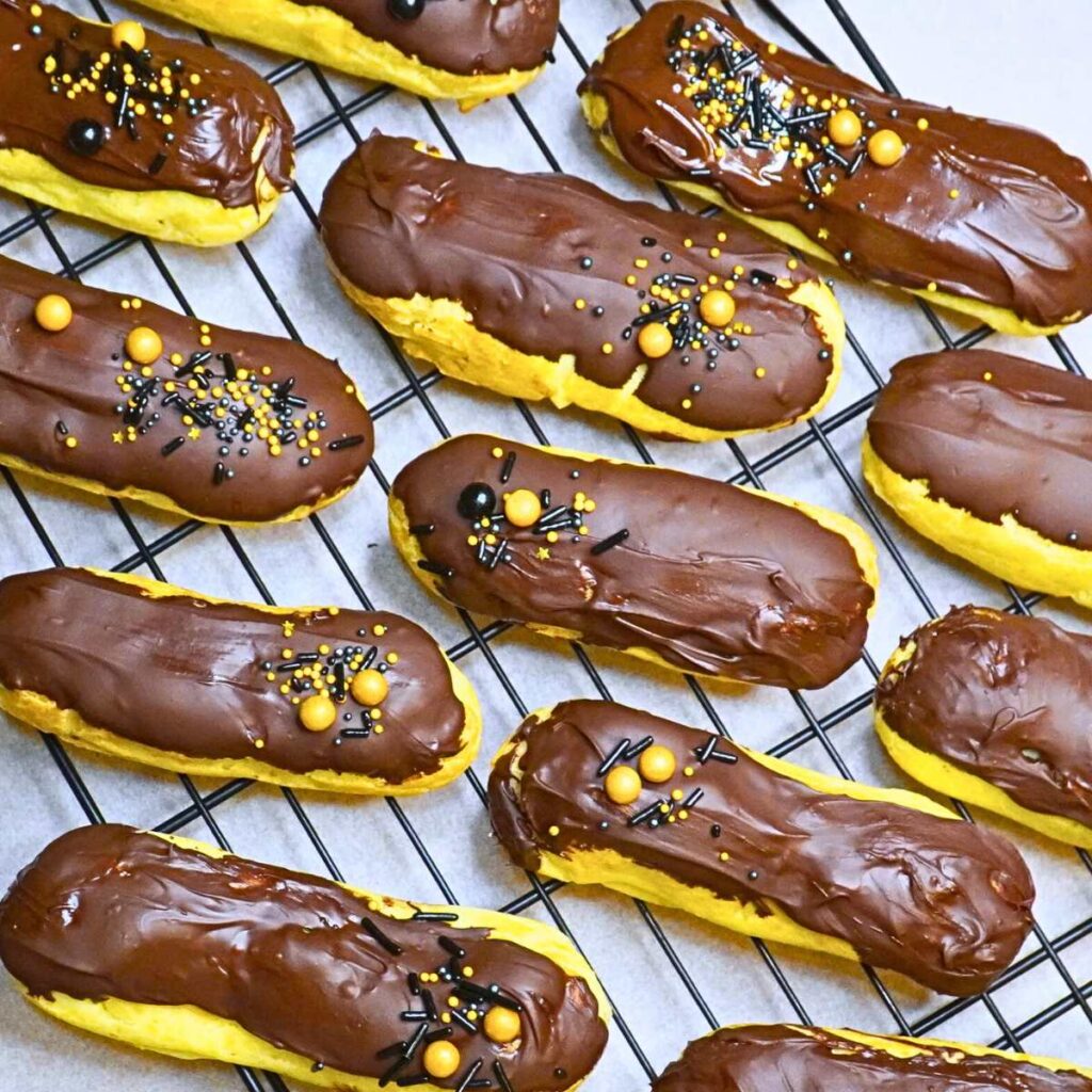 A group of chocolate eclairs decorated with sprinkles.