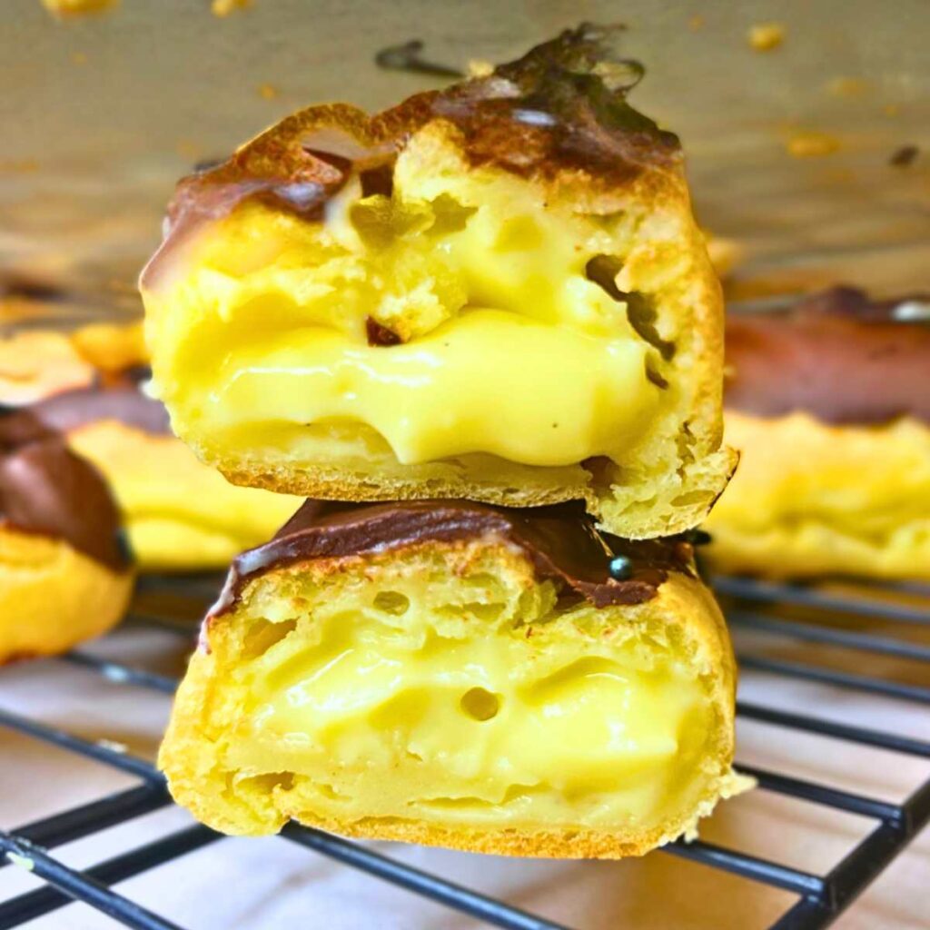 A chocolate eclair cut in half to show the pastry cream inside.