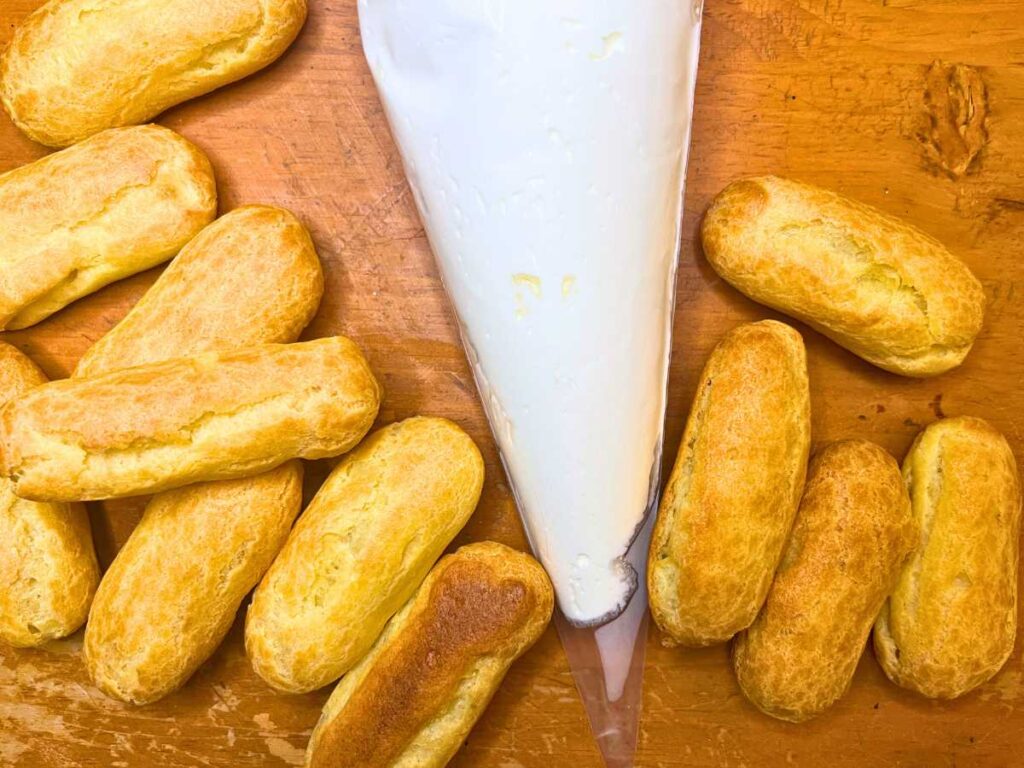 Eclair pastry surrounding a piping bag full of whipped cream.