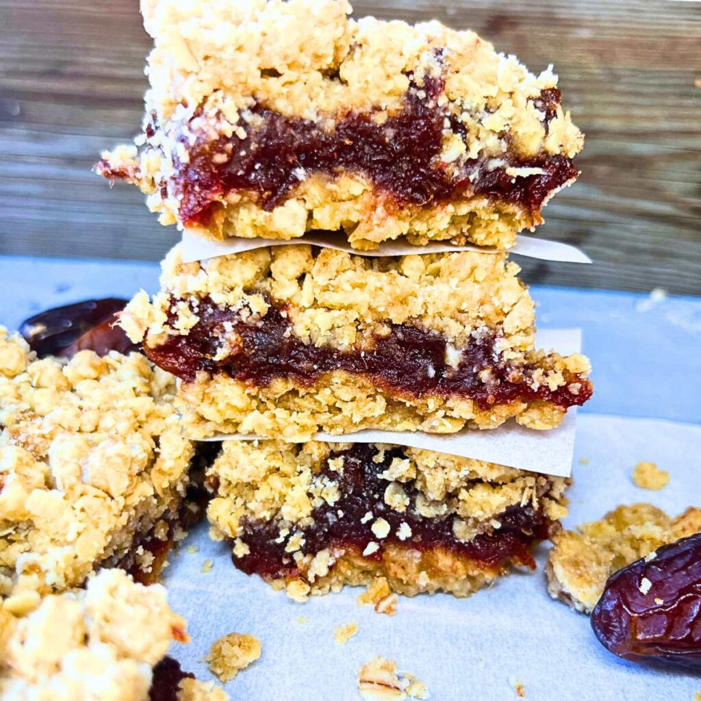 Three date squares piled with parchment paper squares between each one.