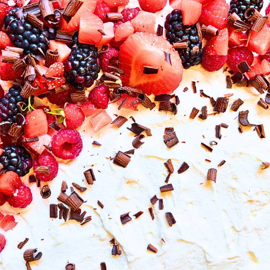 A tres leches cake decorated with fresh berries and shaved chocolate.