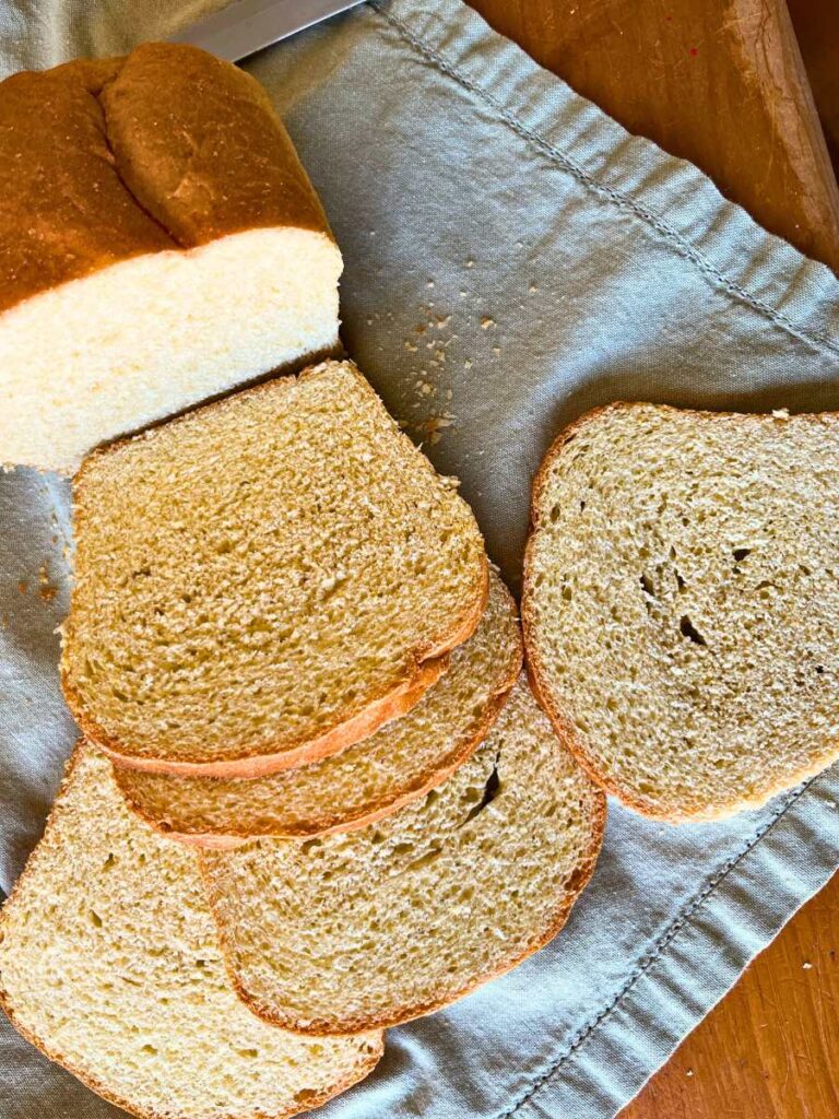 An overhead view of a partially sliced loaf of cornmeal sandwich bread.