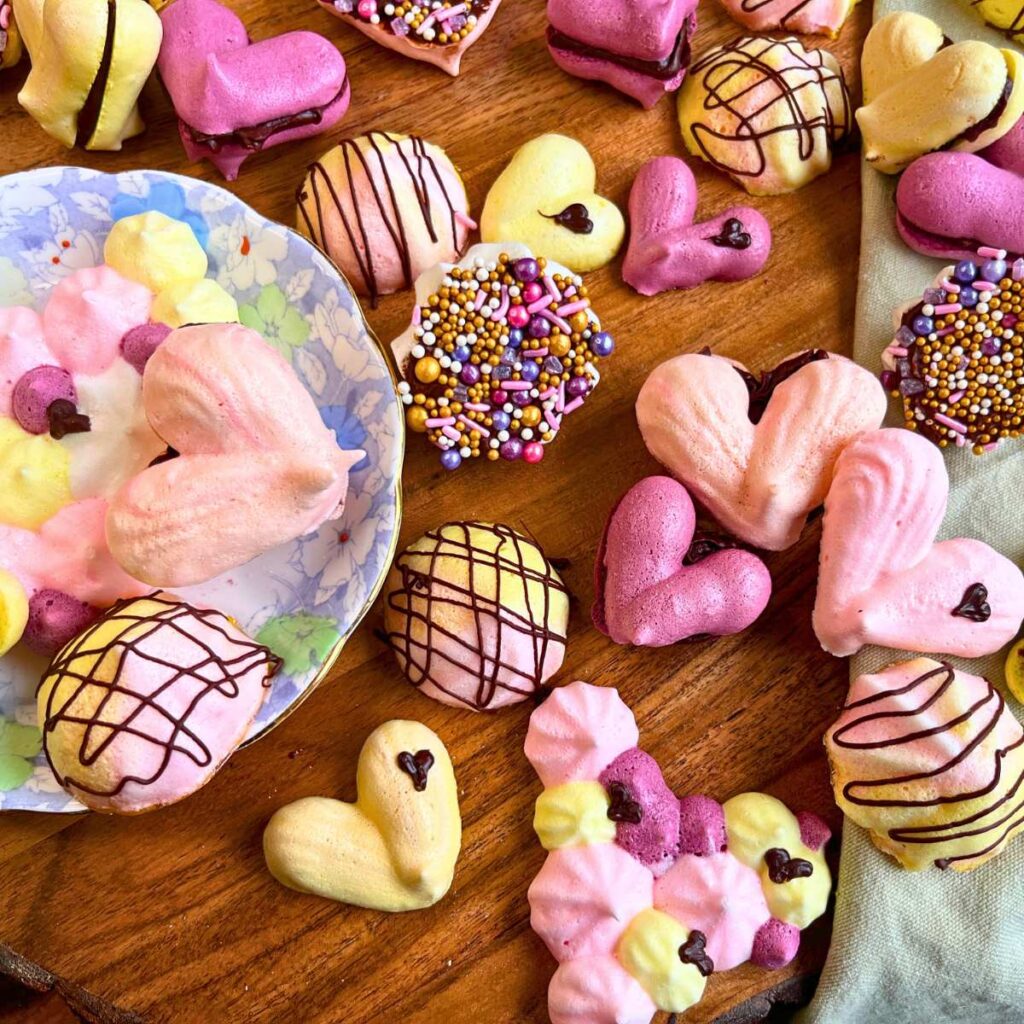 A collection of Valentine's Day themed meringue cookies. Some are decorated with chocolate.