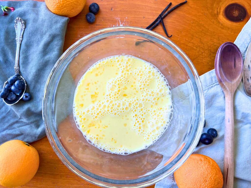 A glass bowl with an egg and milk mixture inside.