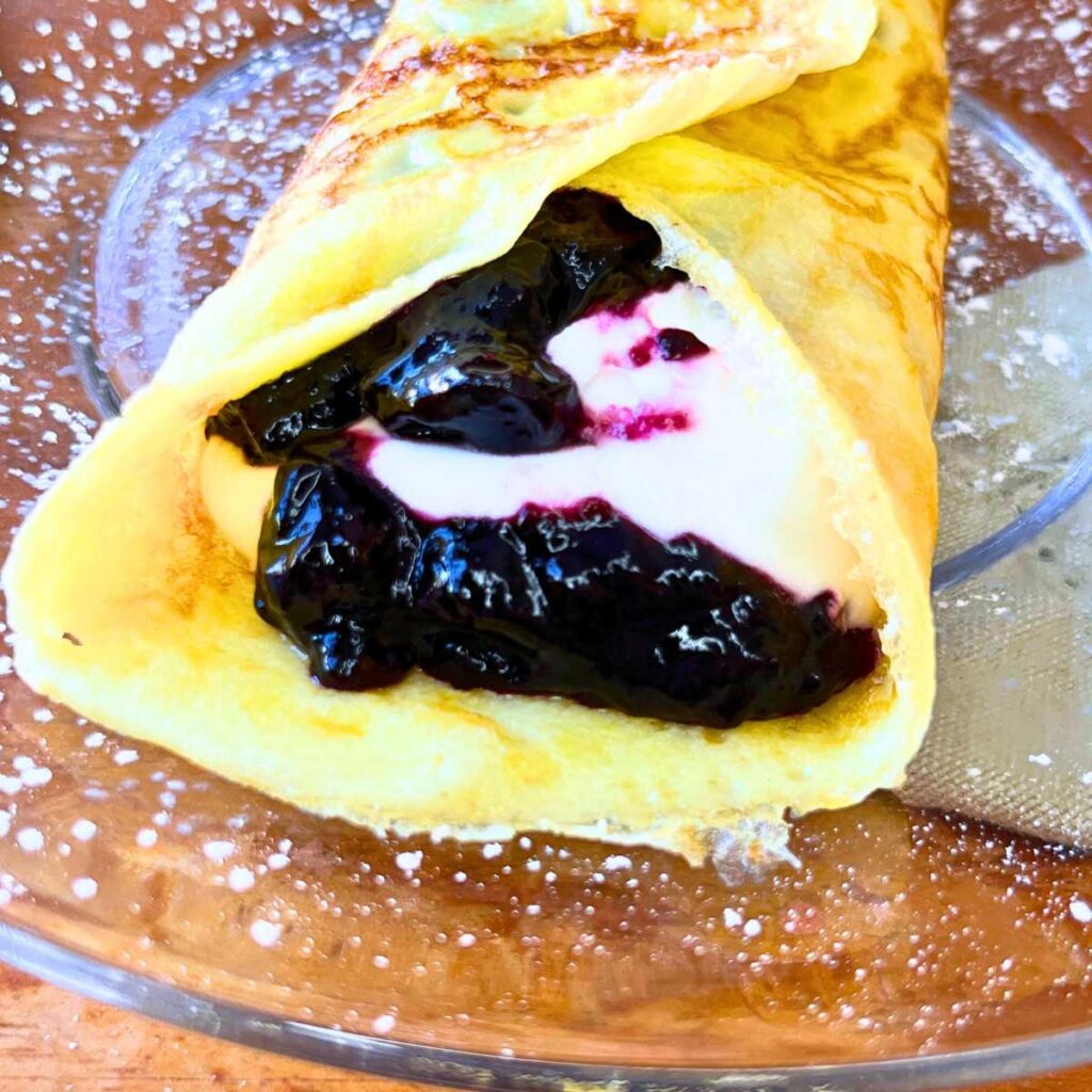 A crêpe filled with blueberry sauce and cream.