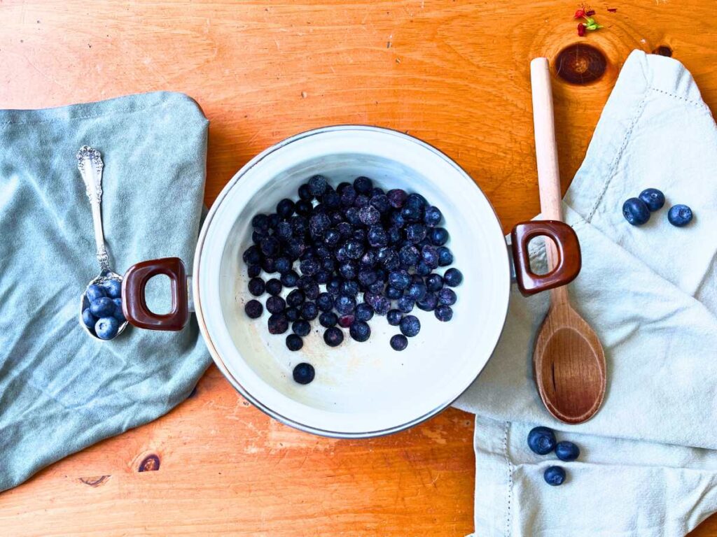 A white sauce pot with blueberries inside.