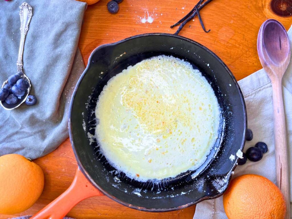 A frying pan with crêpe batter inside.