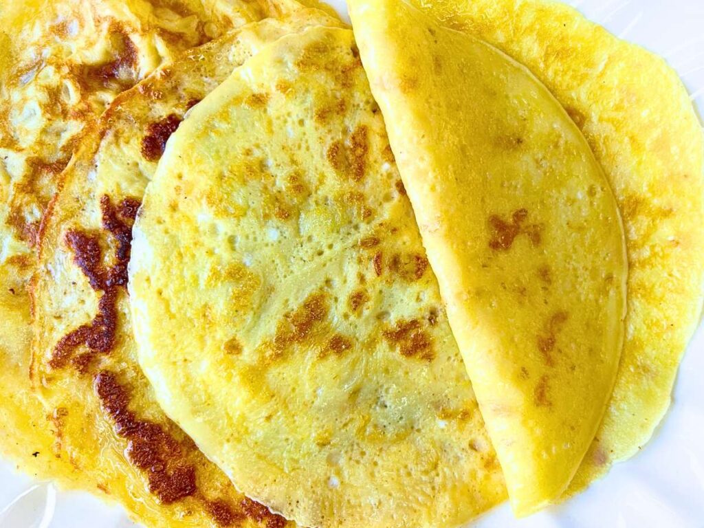 A platter of crêpes. One is folded in half.