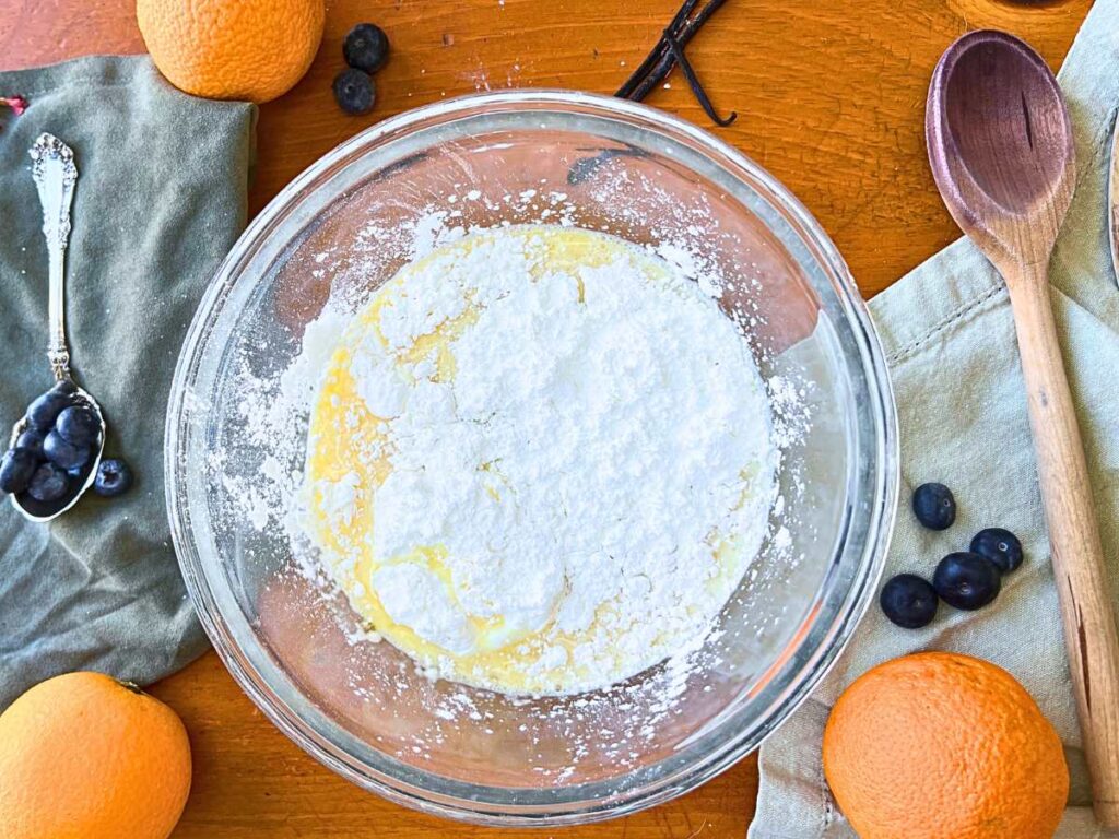 A glass bowl with an egg and milk mixture. There is cornstarch on top.