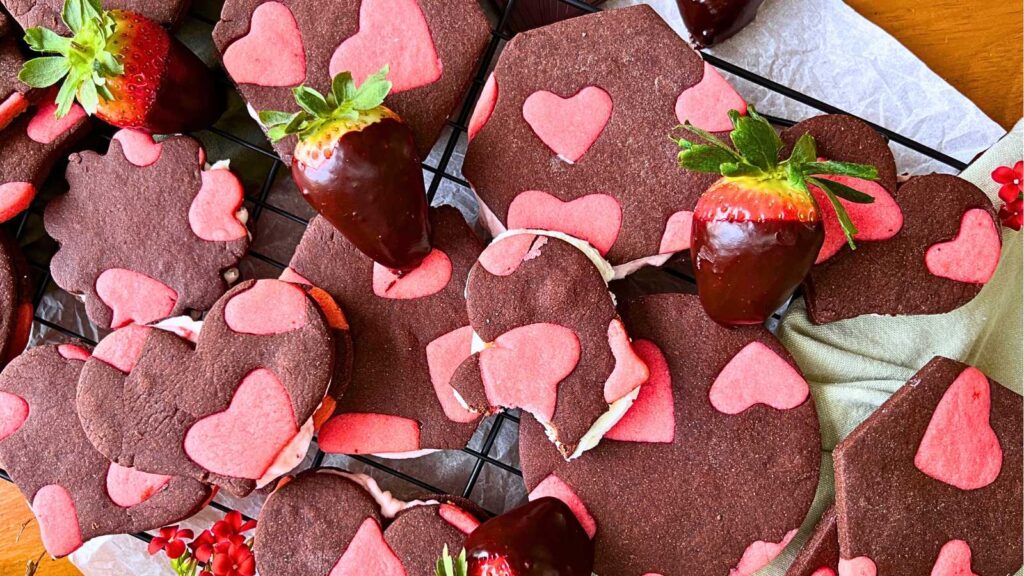 A collection of two-tone strawberry and chocolate sugar cookies surrounded by chocolate covered strawberries.