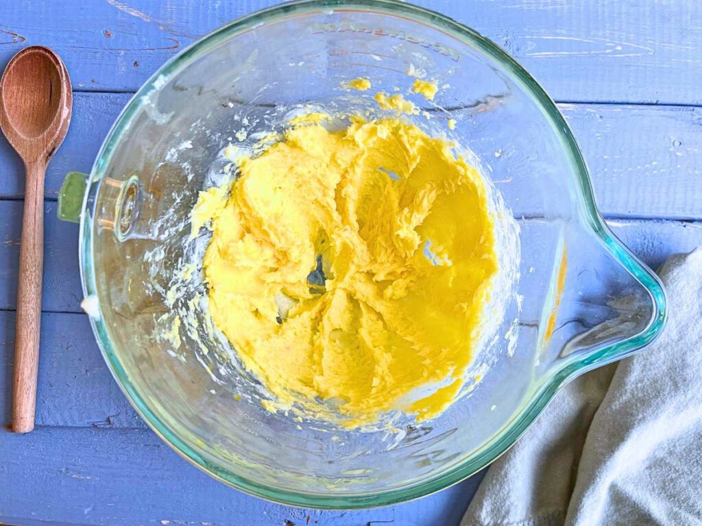 A glass bowl with a creamed butter and sugar mixture inside.