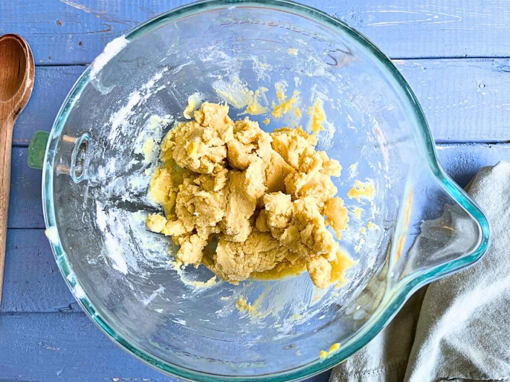 A glass bowl with cookie dough inside.