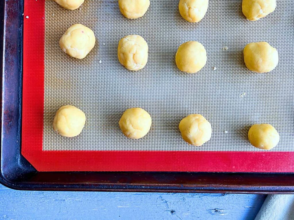 Balls of dough on a lined cookie sheet.