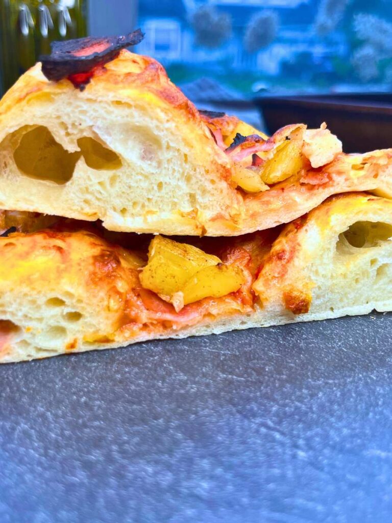 A side view of two slices of pizza showing bubbles inside the crust.
