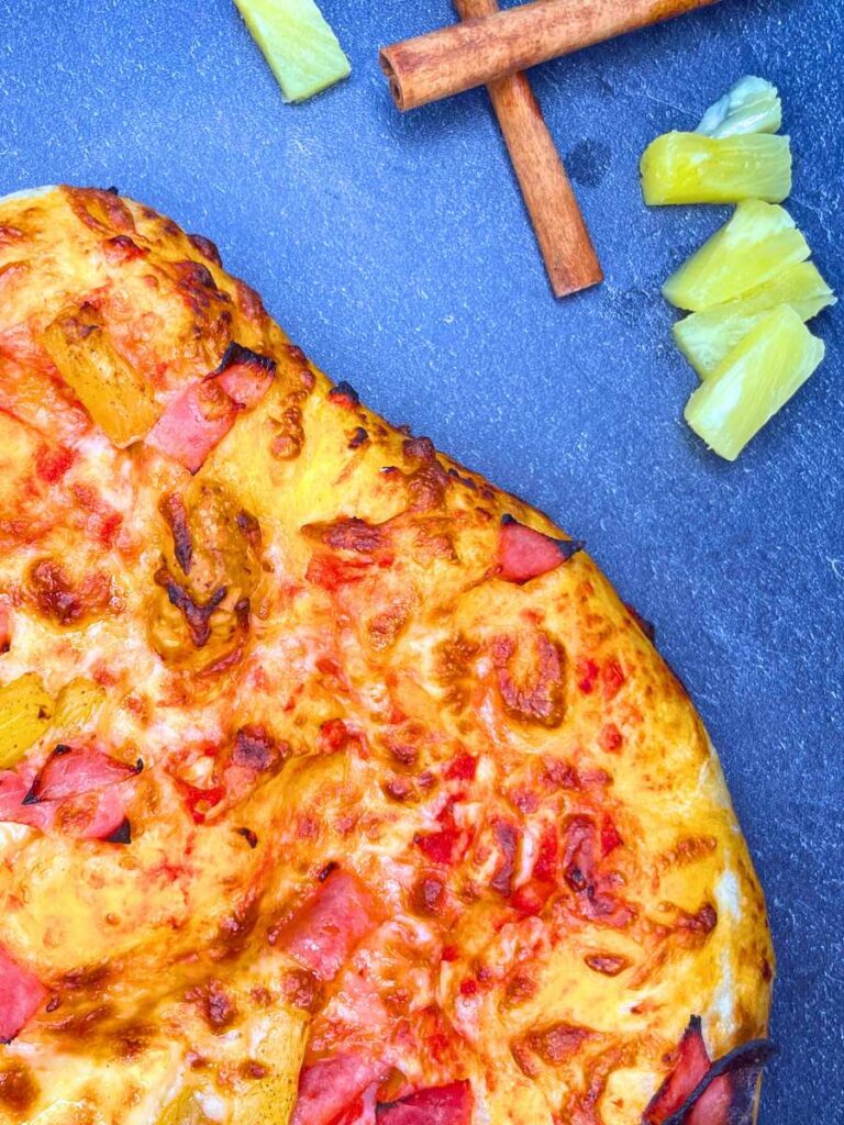 A baked pizza with ham and pineapple.
