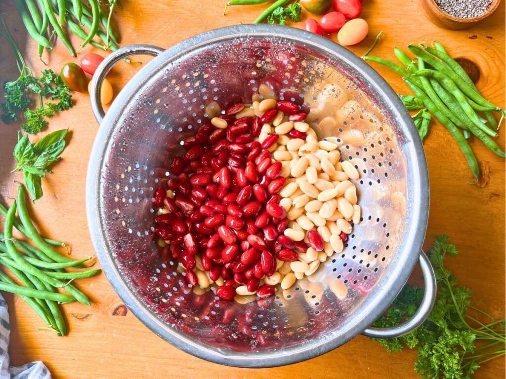Red kidney beans and cannellini beans in a metal colander.
