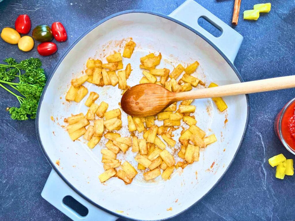 Sautéed pineapple and cinnamon in a sauce pot.