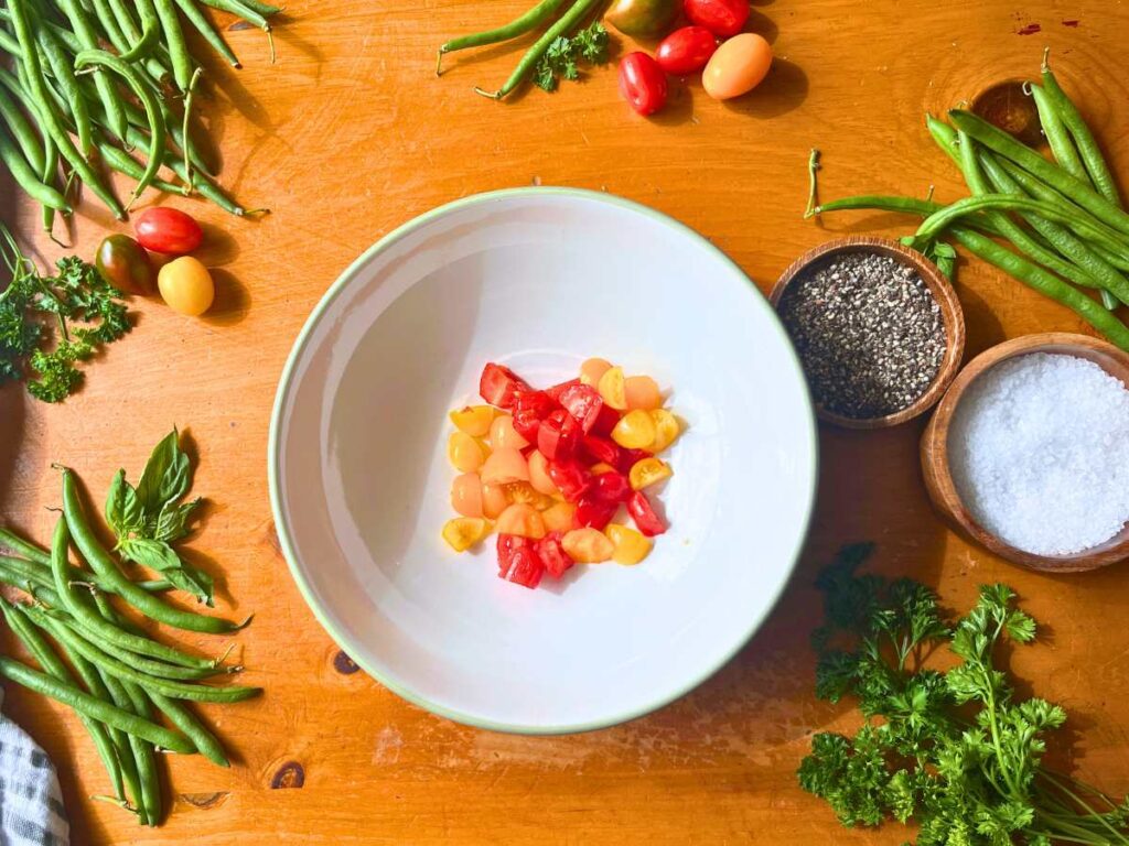 A large white bowl with cut yellow and red cherry tomatoes inside.