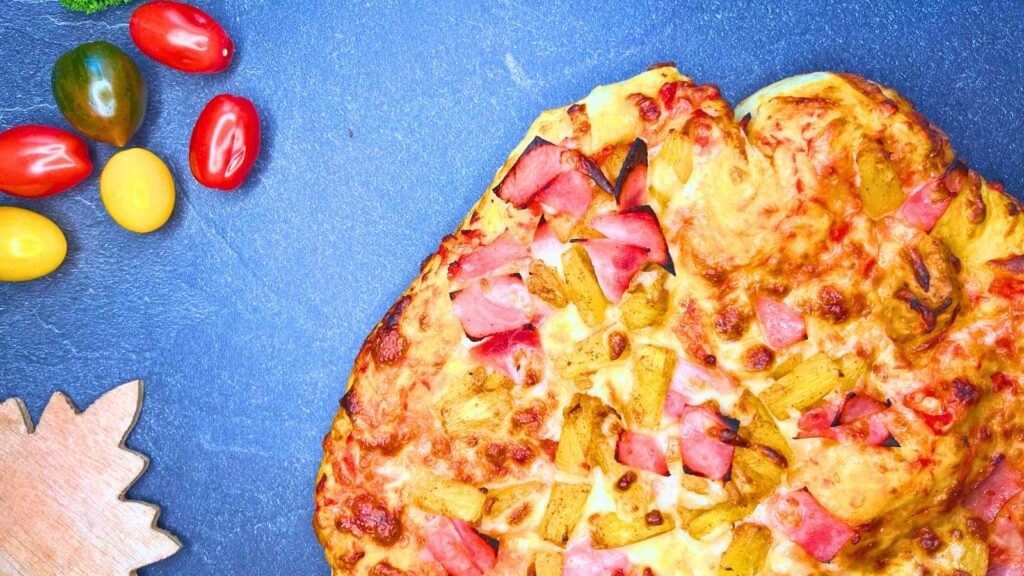 A pizza with ham and pineapple on top.