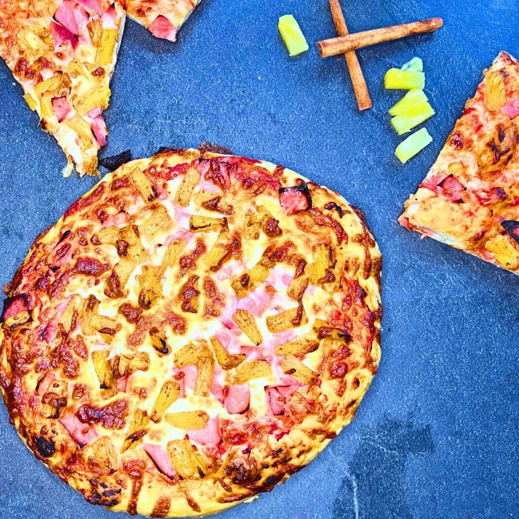 A baked pizza with ham and pineapple on top.
