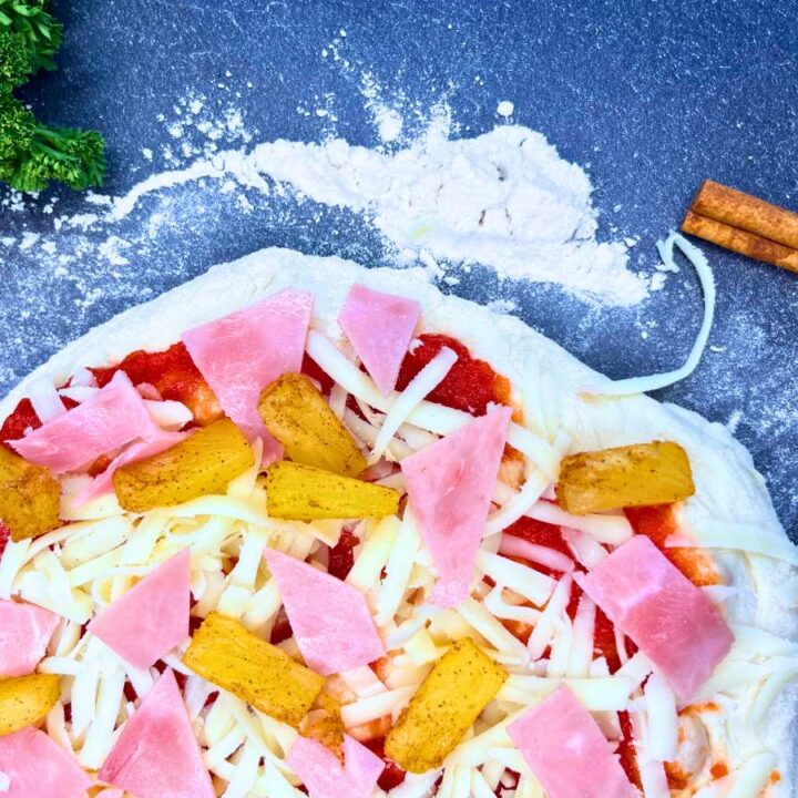 Pizza dough topped with ham and pineapple.