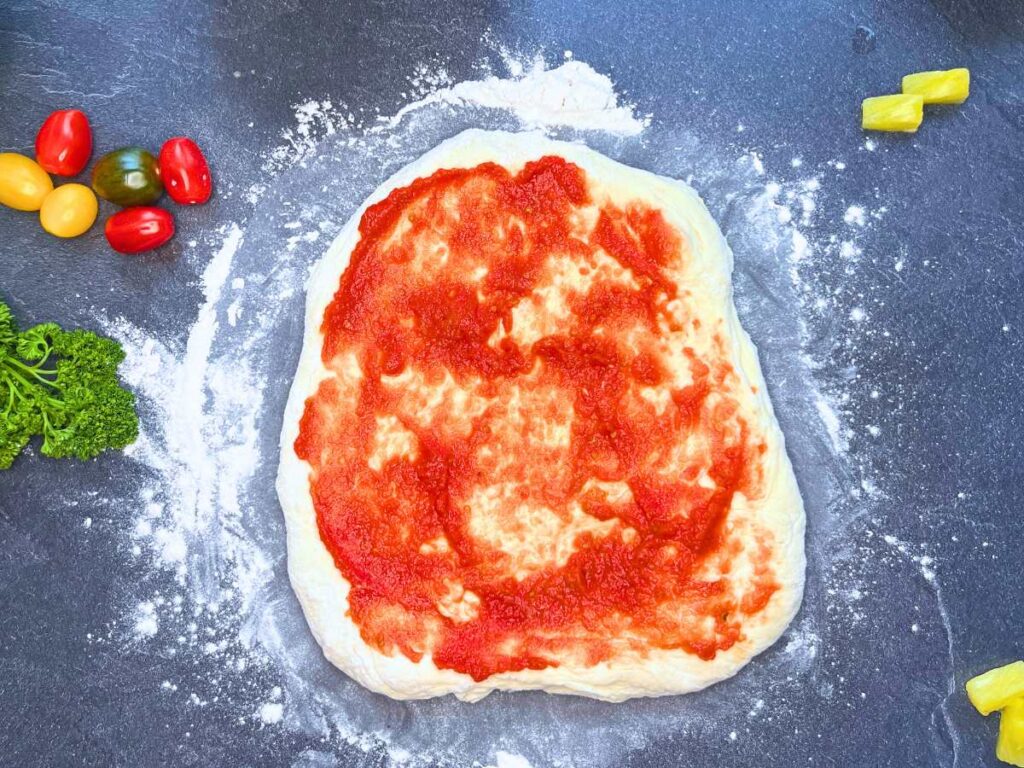 Pizza dough with tomato sauce.
