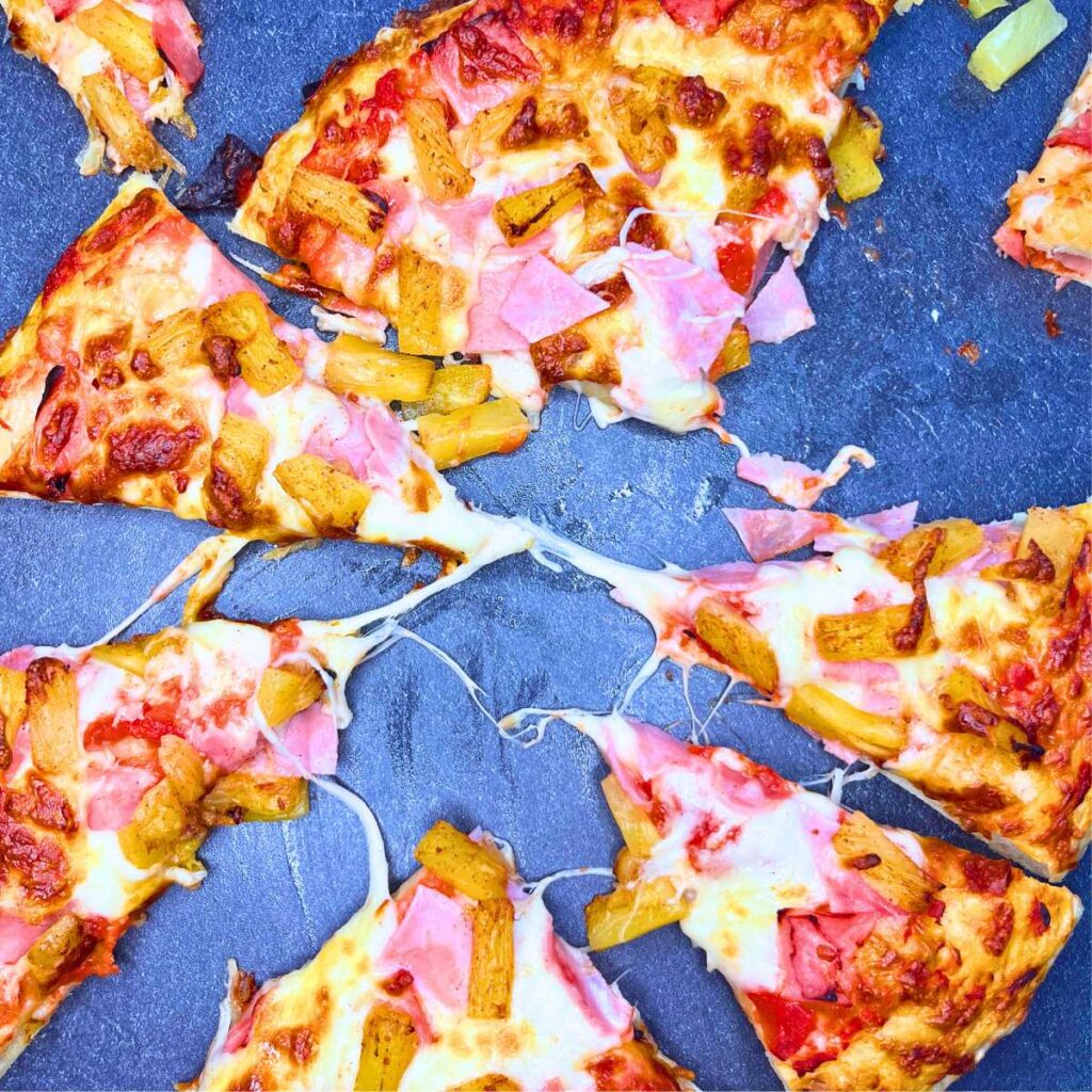 A sliced pizza with ham and pineapple on top.