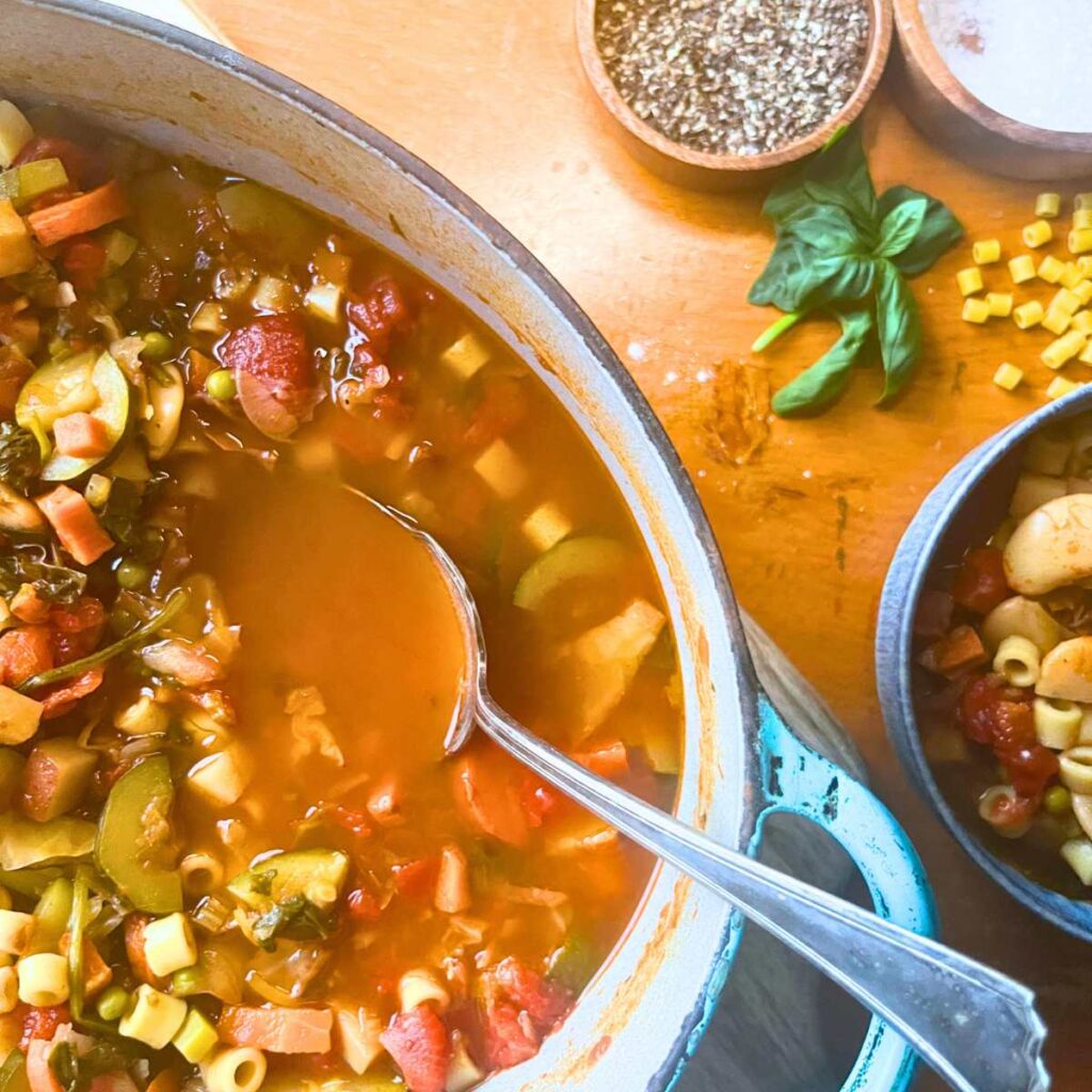 A large blue pot full of vegetable minestrone soup.