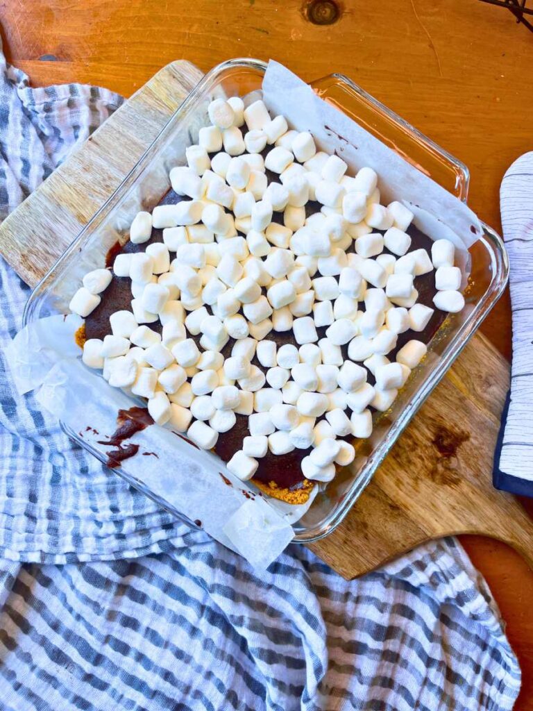 Baked brownies with marshmallows on top. They are in a square glass pan.