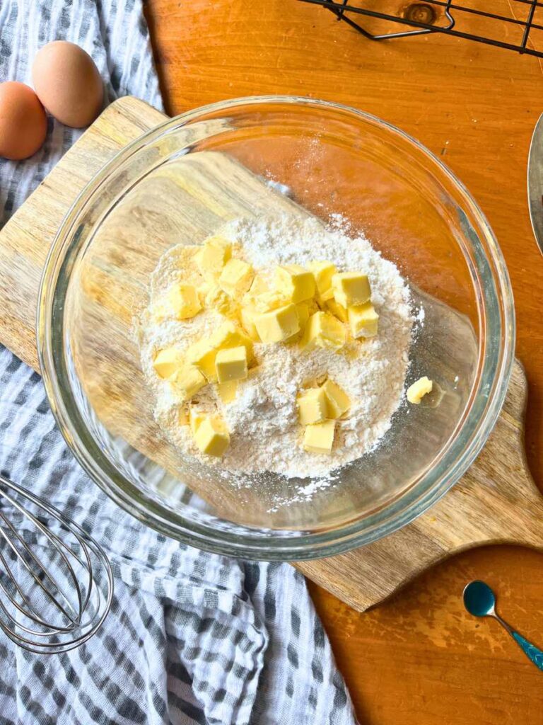 A glass bowl with flour and cubes of butter on top.