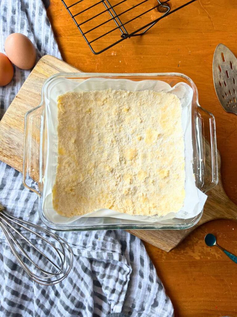 A shortbread base in the bottom of a lined glass square pan.