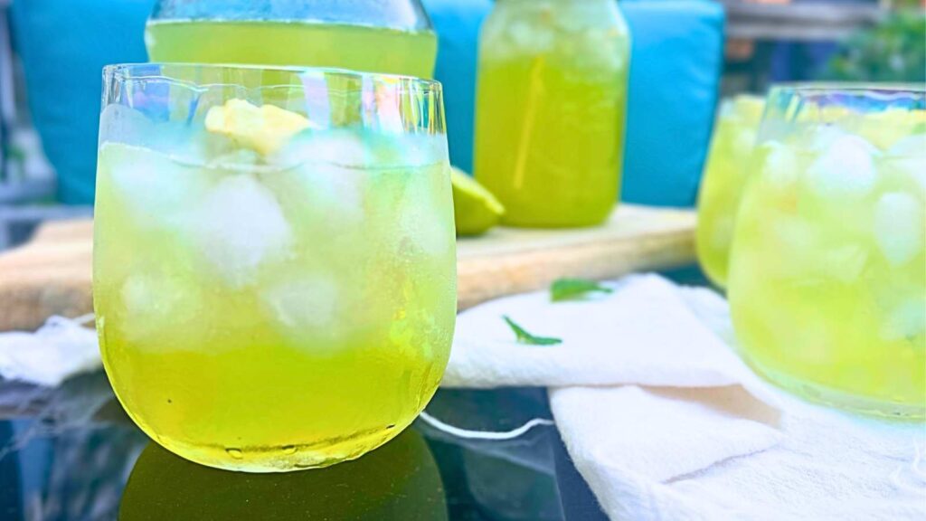 Glasses filled with ice and limeade on a black table.