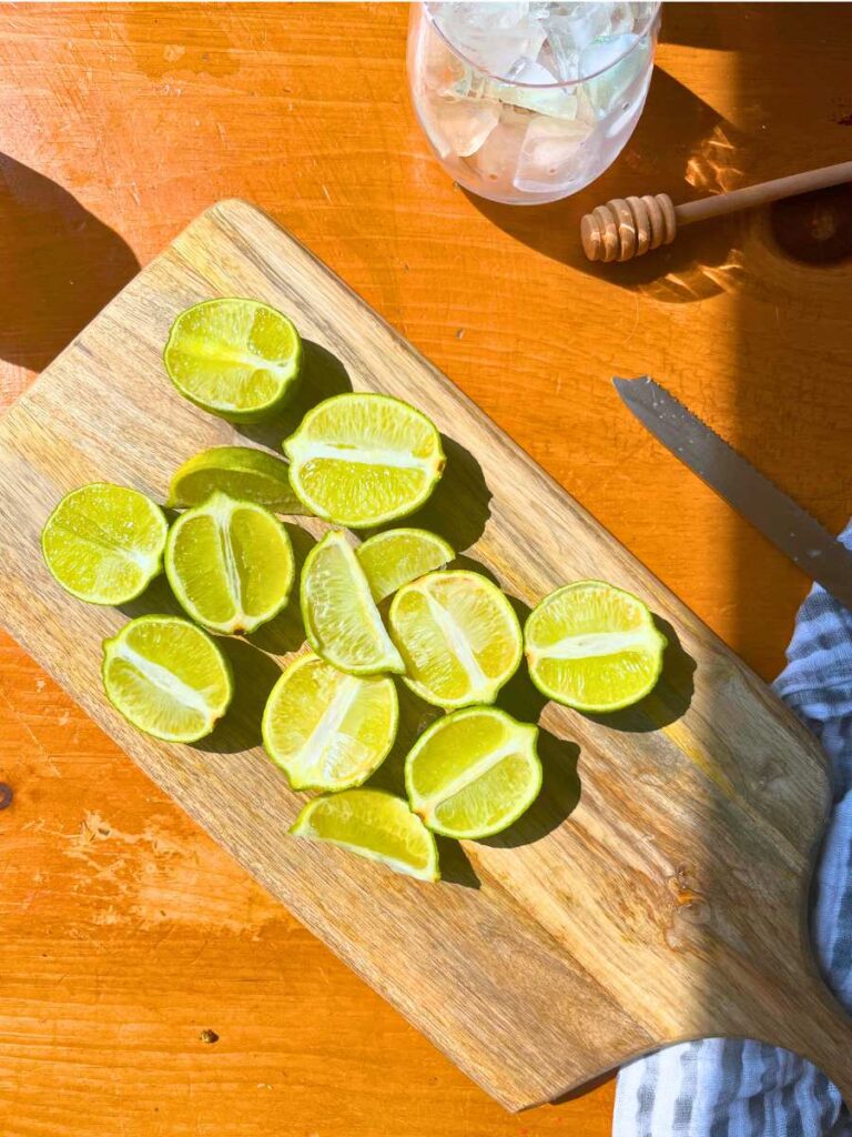 A cutting board with halved limes on top.