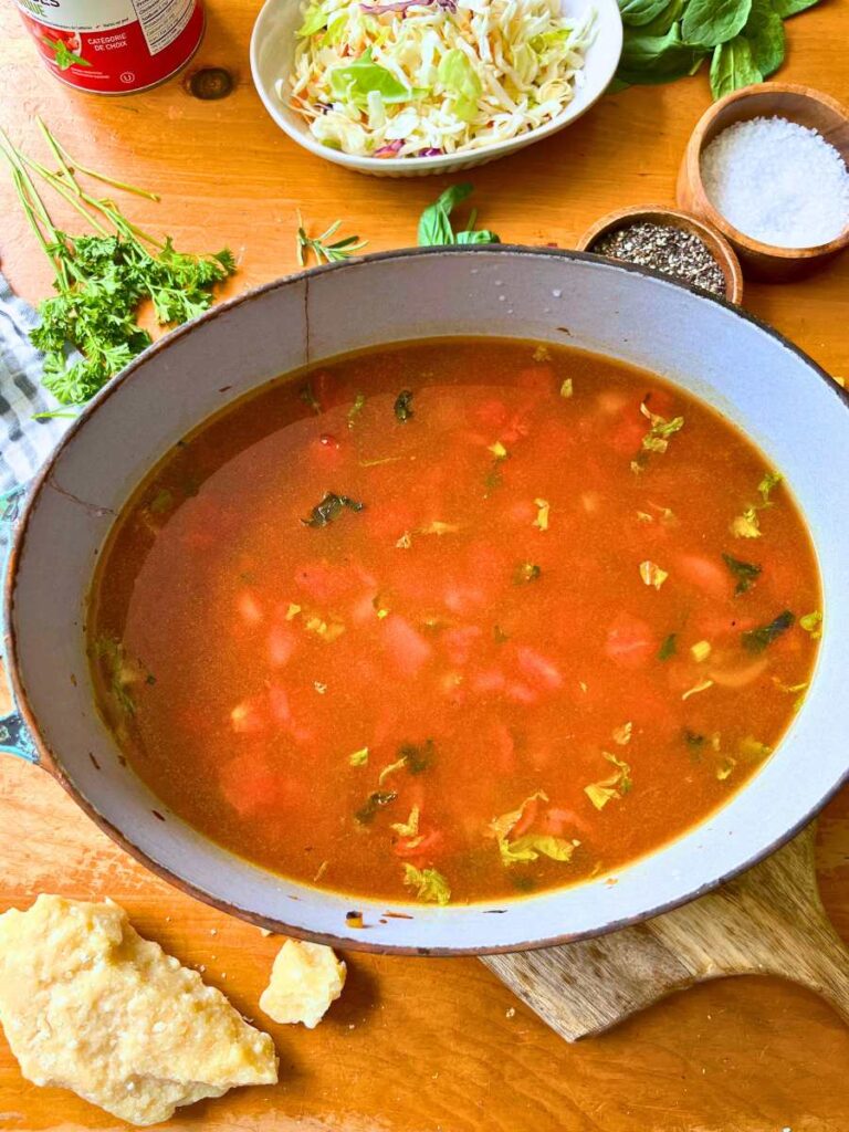 A large pot with cooked vegetables and broth.