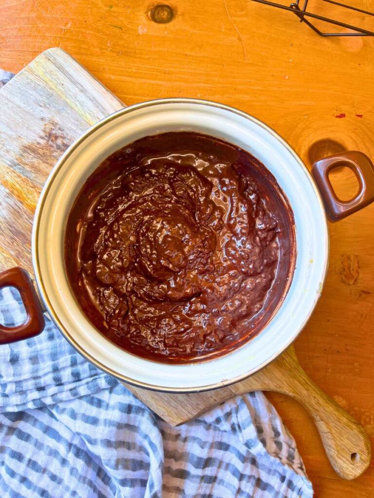Brownie batter in a white sauce pot.