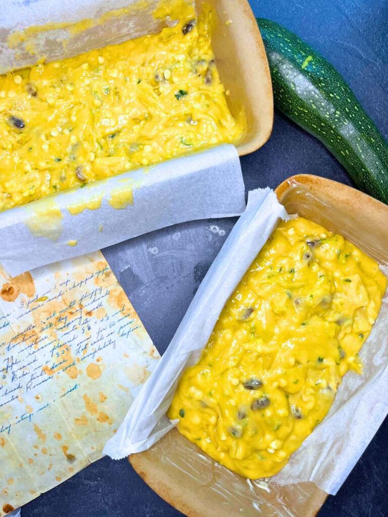 Zucchini bread batter in two parchment lined loaf pans.