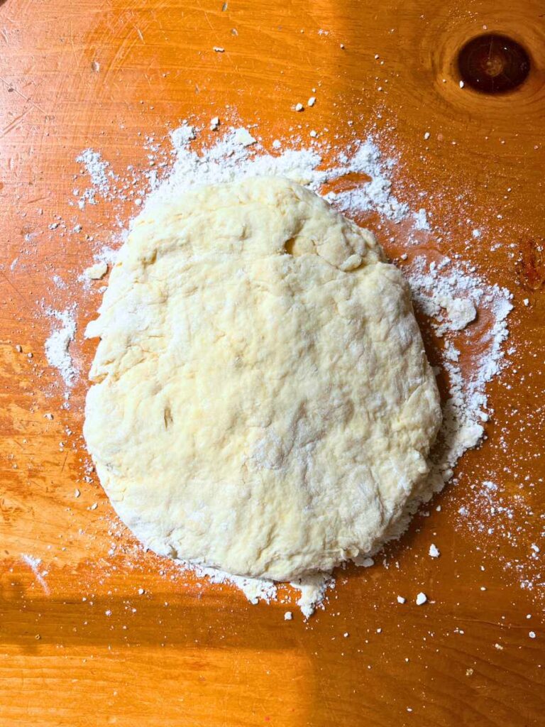 Scone dough pressed out on a wooden table.