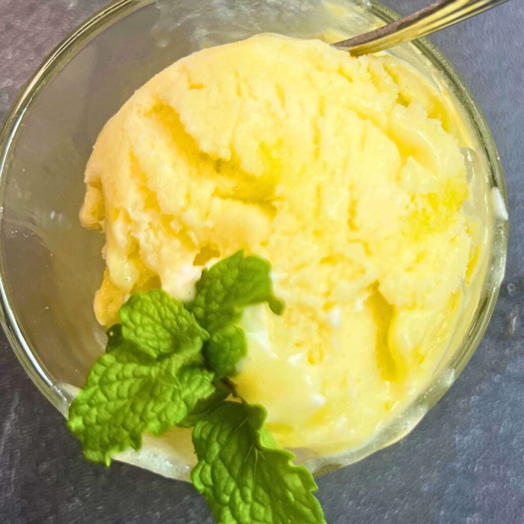 A small glass cup with a scoop of lemon gelato inside.