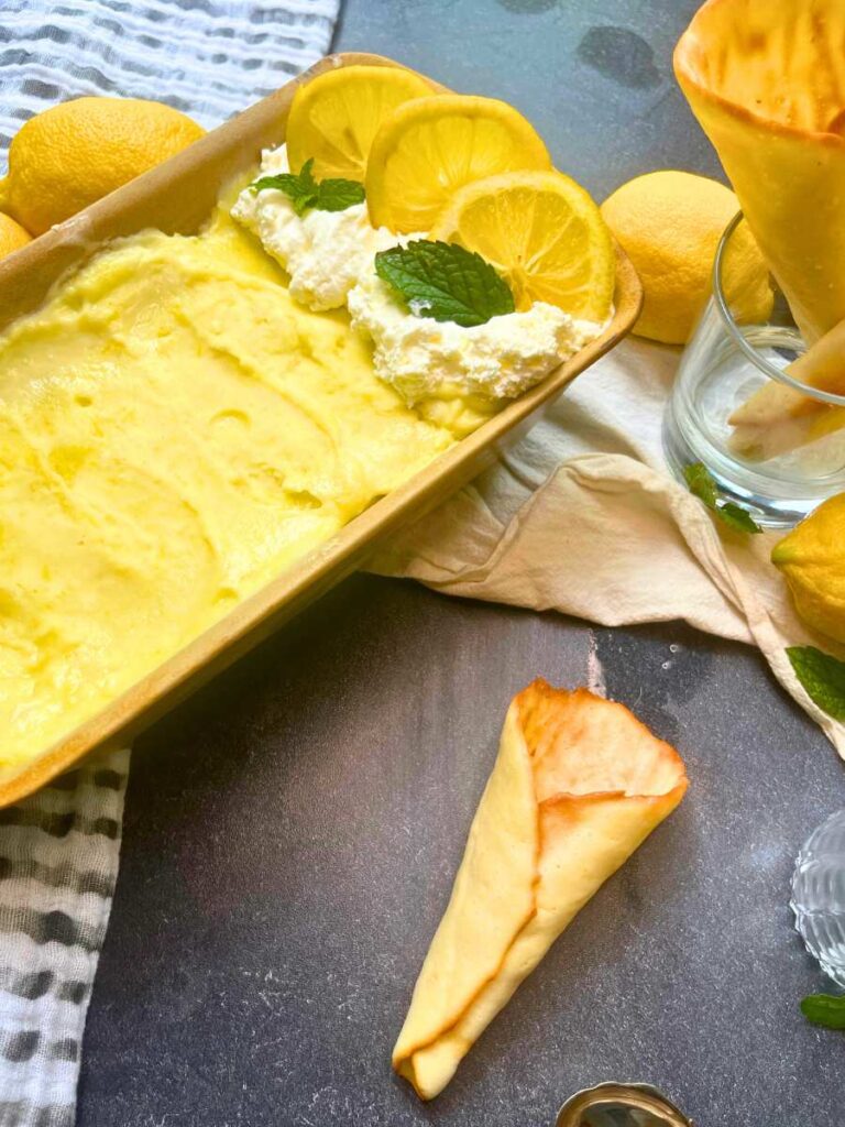 Homemade lemon gelato in a stone pan. There is a homemade ice cream cone beside.