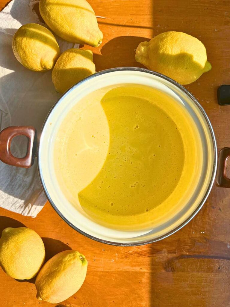 A white sauce pot with a egg yolk and sugar mixture inside.