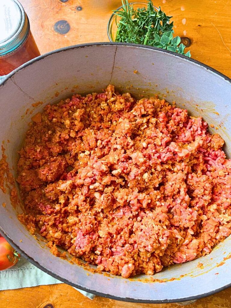 A Dutch oven filled with vegetables and ground meat.